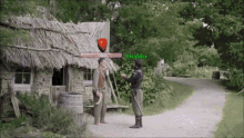 two men are standing in front of a thatched roofed building and one of them has the name boddy on the screen