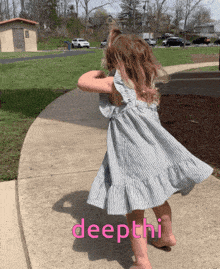 a little girl in a striped dress is standing on a sidewalk with the word deepthi written on the sidewalk