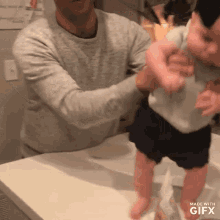 a man is holding a baby in his arms and the gif is made with gifx