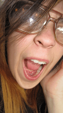 a close up of a woman wearing glasses with her mouth wide open