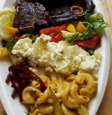 a white plate topped with macaroni and cheese potato salad and steak