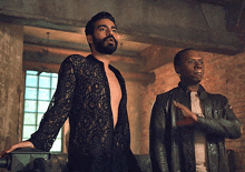 a man in a black lace shirt is standing next to another man