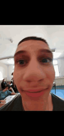 a man is making a funny face in a classroom while sitting at a desk .