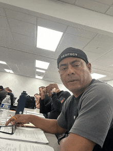 a man wearing a respect headband sits at a desk