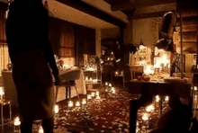 a woman is standing in a room with candles and petals on the floor .