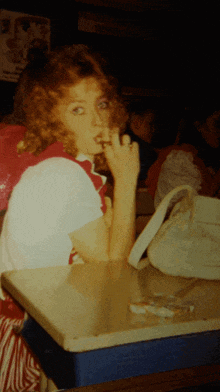 a woman sitting at a table smoking a cigarette in front of a sign that says mcdonalds