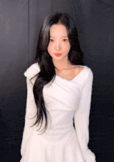 a woman in a white dress with long black hair is looking at the camera