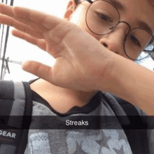 a boy wearing glasses and a backpack is covering his face with his hand and the caption streaks