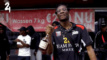 a man holds a bottle of hennessy in front of a sign that says wassen 7 kg