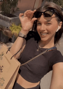 a woman wearing sunglasses and a watch holds a bag that says ' a ' on it