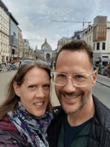 a man and a woman are posing for a picture in front of a building that says ' a & a ' on it