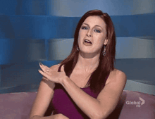 a woman in a purple tank top is sitting on a pink couch with a global hd logo in the corner