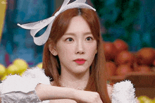 a woman with long red hair wearing a white headband with a bow