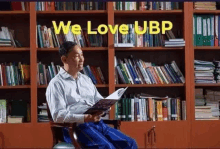 a man is sitting in a chair reading a book in a library .