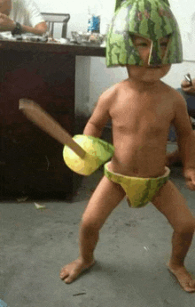 a baby wearing a watermelon helmet and holding a sword