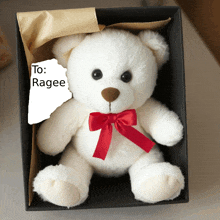 a white teddy bear with a red bow is in a black box with a sticker that says to ragee