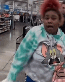 a woman wearing a tie dye tom and jerry shirt is standing in a store .