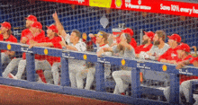 a group of baseball players are sitting in a dugout with a sign that says save 10 % every hour