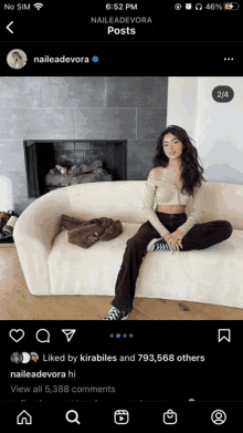 a woman is sitting on a couch in front of a fireplace on a social media page