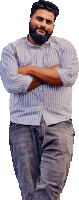 a man with a beard wearing a striped shirt is standing with his arms crossed