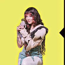 a woman with long hair is holding a parrot