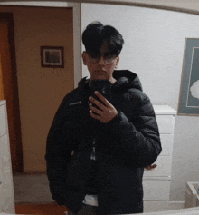 a person wearing a columbia jacket is taking a selfie in a mirror