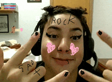 a girl with rock written on her forehead and sad written on her fingers