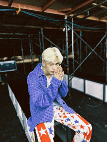 a young man wearing a purple jacket and red white and blue pants