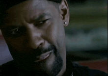 a close up of a man with a beard wearing a black hat and earring .