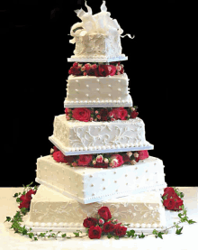 a white wedding cake with red roses and pearls