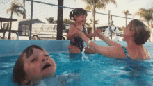 a woman is playing with a little girl in a swimming pool