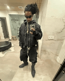 a man with dreadlocks is taking a picture of himself in the mirror