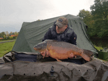 a man holding a large fish in front of a tent that says ' xtr ' on the front