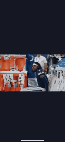 a football player is sitting in a locker room surrounded by coolers .