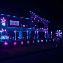 a house decorated with christmas lights and snowflakes at night