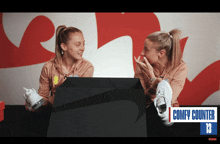 two women are sitting in front of a sign that says comfy counter