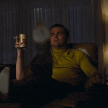 a man in a yellow shirt is sitting in a chair and pointing