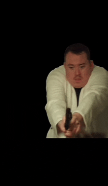 a man in a white robe is pointing a gun at someone .