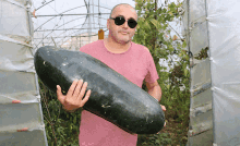 a man wearing sunglasses is holding a very large black object