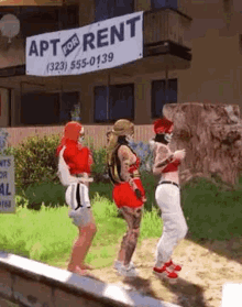 a group of people are standing in front of a building with a sign that says apartment for rent .