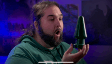 a man with long hair and a beard is holding a green object