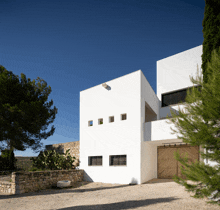 a white building with a wooden garage door and a stone wall