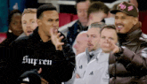 a man wearing a supreme hoodie is pointing at something