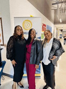 three women standing in front of a sign that says ' dominion ' on it