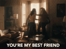 two women are dancing in a living room with the words " you 're my best friend " in the corner