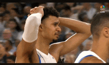 a basketball player holds his head in his hands while another player looks on