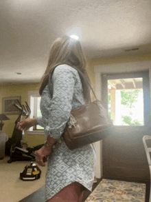 a woman in a blue shirt is carrying a brown leather purse