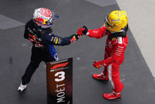 two racing drivers shake hands in front of a moet sign