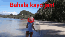 a woman wearing a red hat stands on a beach with the words ' bahaya kayo jan ' written in red