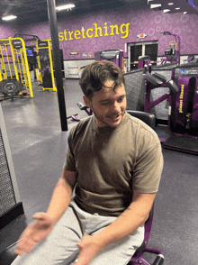 a man is sitting in front of a stretching sign